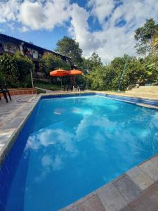 a large blue swimming pool with an umbrella at Agradable casa de Campo Villa Maruja. in Palmira