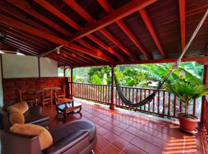 a screened in porch with a couch and a hammock at La Casa de las Flores Hostal in Jardin