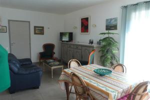 ein Wohnzimmer mit einem Tisch, Stühlen und einem TV in der Unterkunft GITE DE L UBAC in Lafare
