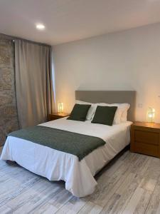 een slaapkamer met een groot wit bed en 2 nachtkastjes bij Quinta do Avô - Casa de Campo in Terras de Bouro