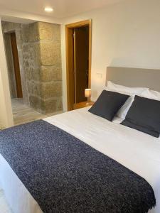 a bedroom with a large bed and a stone wall at Quinta do Avô - Casa de Campo in Terras de Bouro