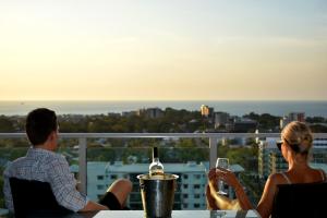a man and a woman sitting at a table with a glass of wine at H on Mitchell Apartment Hotel in Darwin