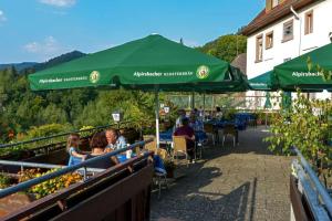 eine Gruppe von Menschen, die unter einem grünen Schirm sitzen in der Unterkunft Landgasthof-Pension Ochsen in Forbach