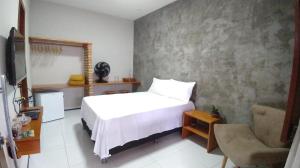 a bedroom with a white bed and a chair at Casa do Tchesko in Viçosa do Ceará