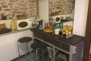 a kitchen with a counter with stools and a microwave at maison Appart du mont july in Ceyzériat