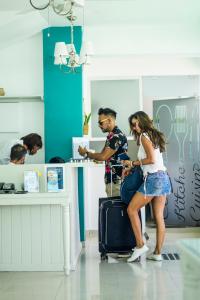 Um homem com uma mulher sentada numa mala. em Green Coast Beach Hotel em Punta Cana