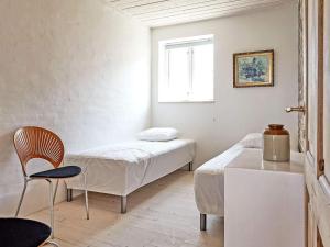 a room with two beds and a chair and a window at 6 person holiday home in Svaneke in Svaneke