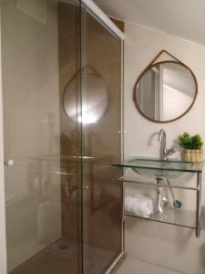 cabina de ducha de cristal con lavabo y espejo en Apartamento Temporada Palácio Quitandinha em Petrópolis RJ en Petrópolis