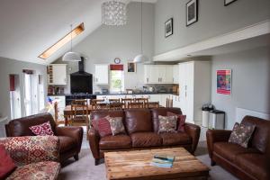 uma sala de estar com sofás e uma mesa e uma cozinha em Wellstone Cottages - Coach House em Pembrokeshire