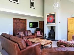 a living room with leather furniture and a wooden table at Wellstone Cottages - Coach House in Pembrokeshire