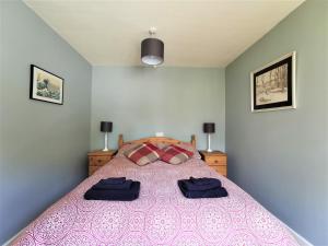 a bedroom with a pink bed with two pillows on it at Wellstone Cottages - Coach House in Pembrokeshire