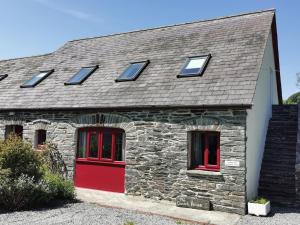 uma casa de pedra com portas e janelas vermelhas em Wellstone Cottages - Coach House em Pembrokeshire