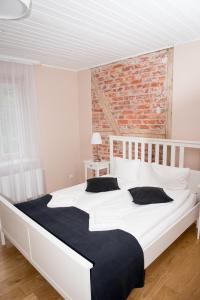 Cama blanca grande en habitación con pared de ladrillo en Liepa en Šilutė