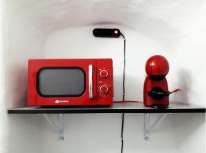 a red microwave sitting on a shelf next to a red object at ALCENTRO Orange Home in Venafro +10 photos