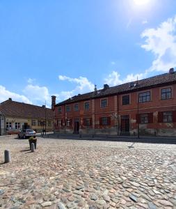 a large brick building with a car parked in front of it at Arāja apartamenti in Kuldīga