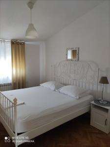 a bedroom with a white bed with a white headboard at Apartment Marco in Zadar