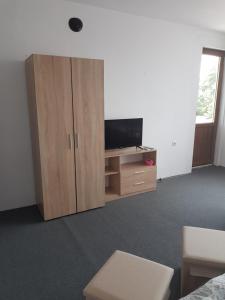a living room with a tv and a wooden cabinet at Guest Rooms Radost in Balchik