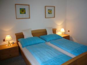 - une chambre avec un lit avec des draps bleus et deux lampes dans l'établissement Ferienwohnungen Haus Peer, à Bad Goisern