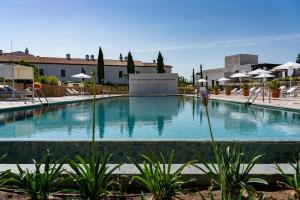a large swimming pool in a resort with umbrellas at Hospes Palacio de Arenales & Spa in Cáceres
