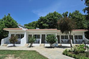 een wit huis met stoelen en bomen bij Elizabeth Studios in Skiathos-stad