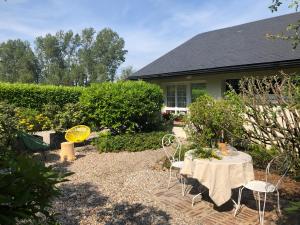 - un jardin avec une table et des chaises en face d'une maison dans l'établissement Jardin des Pérelles, à Varengeville-sur-Mer