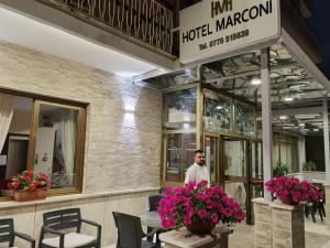 Un uomo in piedi di fronte a un hotel con dei fiori di Hotel Marconi a Fiuggi
