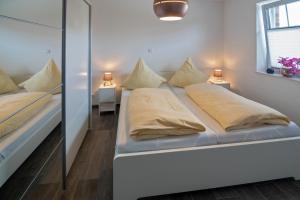 - une chambre blanche avec 2 lits et un miroir dans l'établissement Küstenkäthe, à Dornumersiel