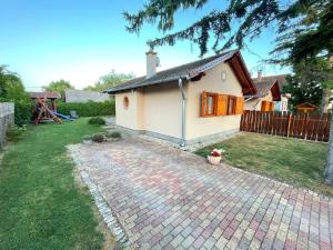 a small white house with a brick driveway at Tölgyfa Apartman in Balatonkeresztúr