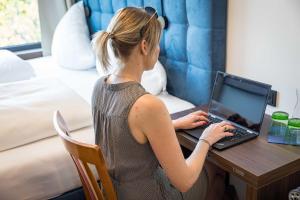 een vrouw aan een bureau met een laptop bij On The Way 24 - Sauna & Golfsimulator inklusive in Spittal an der Drau