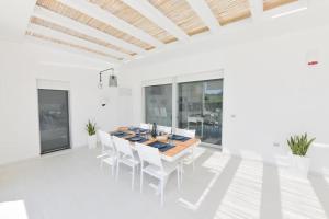ein weißes Esszimmer mit einem Holztisch und Stühlen in der Unterkunft Il marchese in piscina in San Pietro in Bevagna