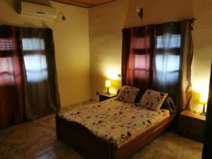 a bedroom with a bed with two windows and two lamps at ROMO house in Cotonou