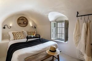 - une chambre avec un lit et un chapeau sur une table dans l'établissement Caldera Houses Oia, à Oia
