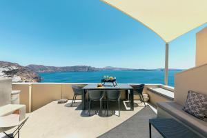 Zimmer mit einem Tisch und Stühlen auf einem Balkon in der Unterkunft Caldera Houses Oia in Oia