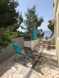 un patio con sillas, una sombrilla y una mesa en Nemira beach apartments, en Omiš
