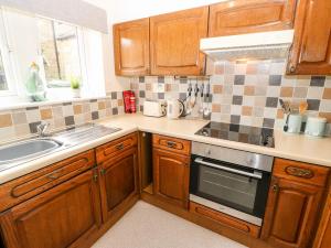 a kitchen with wooden cabinets and a sink and a stove at Duck Egg Cottage in Keighley