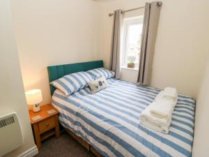a bedroom with a blue and white striped bed with a window at Duck Egg Cottage in Keighley