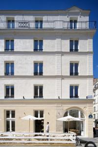 a man standing in front of a building with umbrellas at My Maison In Paris - Champ de Mars in Paris