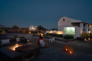 a woman sitting on the ground in front of a house at Le Grand Blue Villa in Akrotiri