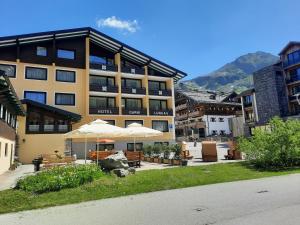 ein Gebäude mit Tischen und Sonnenschirmen davor in der Unterkunft Hotel Bella in Obertauern