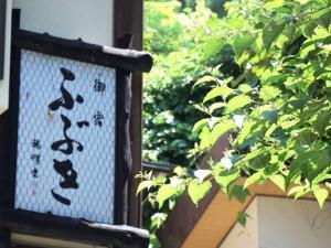 une fenêtre avec des écrits chinois à côté d'une brousse dans l'établissement Oyado Fubuki, à Nozawa Onsen