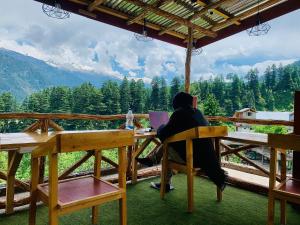 a person sitting at a table with a laptop at Jungle by sturmfrei Manali in Manāli