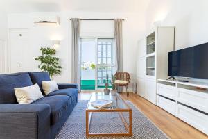 un soggiorno con divano blu e TV di Genteel Home Castilla Terrace a Siviglia
