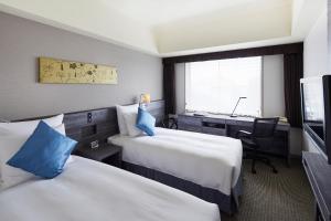 a hotel room with two beds and a desk at ANA Crowne Plaza Kanazawa by IHG in Kanazawa
