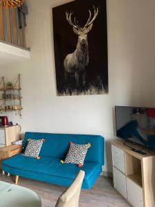 un sofá azul en una sala de estar con una foto de un ciervo en Appartement Hauteur Barcelonnette Vue Exceptionnelle en Barcelonnette