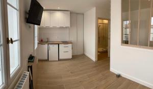 a kitchen with white cabinets and a wooden floor at Réalaplage studio de charme sur Rivedoux in Rivedoux-Plage