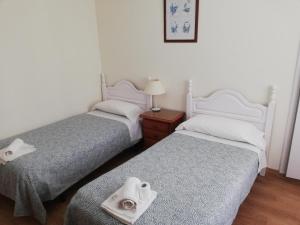 two beds in a room with towels on the beds at Pension Santa Rita in Santiago de Compostela