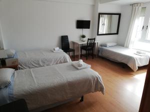 a room with two beds and a desk with a chair at Pension Santa Rita in Santiago de Compostela