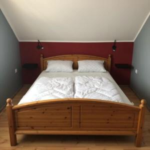 a bedroom with a wooden bed with two pillows at Hanga Apartman in Tiszafüred