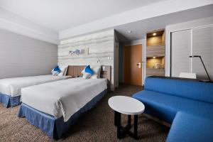 a hotel room with two beds and a blue couch at ANA Crowne Plaza Kanazawa by IHG in Kanazawa