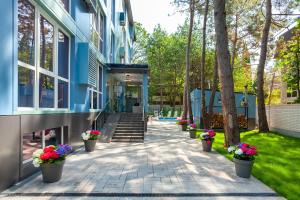 a walkway outside of a building with potted flowers at Wellness СПА-Отель Грейс Калифорния in Adler